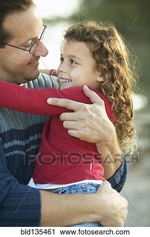 Stock Image - Father hugging daughter outdoors. Fotosearch