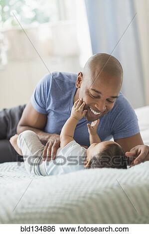Father playing with baby on sofa View Large Photo Image Stock Photograph - Father playing with baby on sofa. Fotosearch
