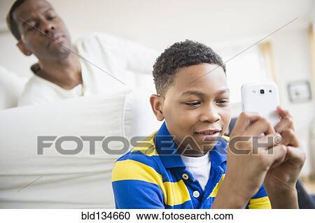 Father watching son use cell phone View Large Photo Image Stock Image - Father watching son use cell phone. Fotosearch