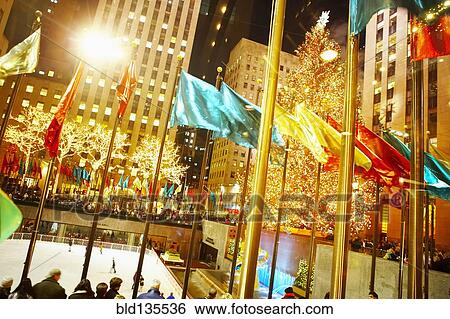 Stock Photograph - Flags flying over Rockefeller Center at night, New York, New York, United States. Fotosearch