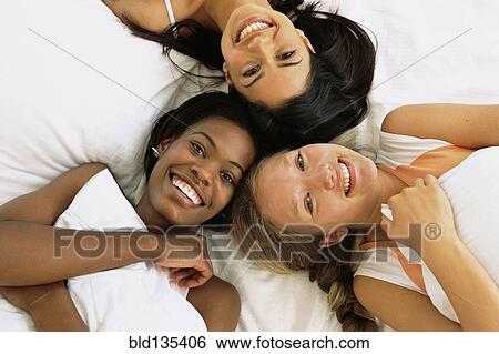 Stock Photograph - Friends relaxing together on bed. Fotosearch