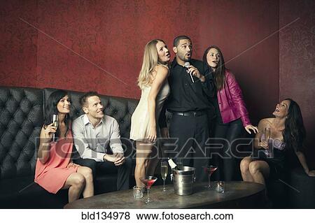 Stock Photo - Friends singing karaoke together in nightclub. Fotosearch