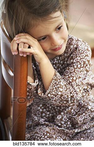 Picture - Girl sitting in wooden chair. Fotosearch