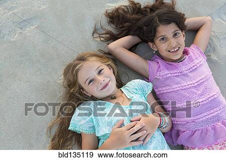 Girls laying in sand on beach View Large Photo Image Stock Photo - Girls laying in sand on beach. Fotosearch