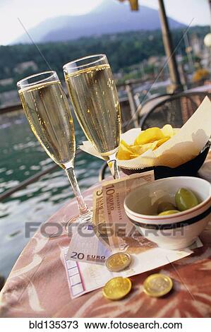 Glasses of champagne, chips, olive and money at sidewalk cafe View Large Photo Image Stock Image - Glasses of champagne, chips, olive and money at sidewalk cafe. Fotosearch