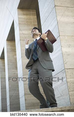 Hispanic businessman cheering on city street View Large Photo Image Stock Image - Hispanic businessman cheering on city street. Fotosearch