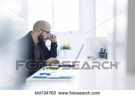 Stock Image - Hispanic businessman working at desk. Fotosearch