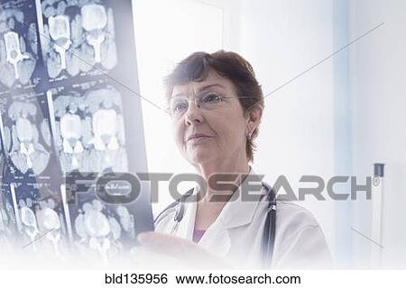 Stock Photograph - Hispanic doctor examining x-rays in office. Fotosearch
