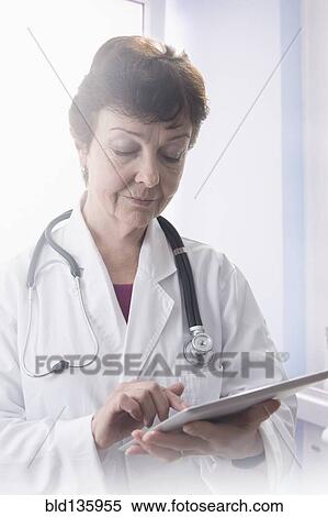 Stock Photography - Hispanic doctor using tablet computer in office. Fotosearch