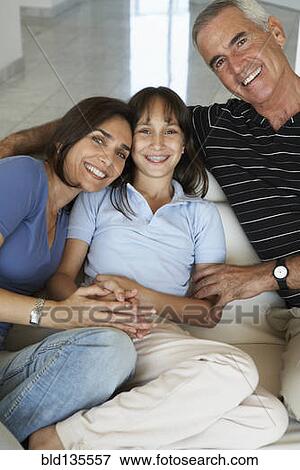 Stock Photo - Hispanic family smiling together on sofa. Fotosearch