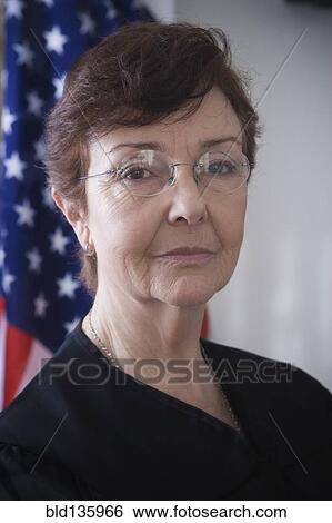 Stock Photograph - Hispanic judge posing by American flag. Fotosearch