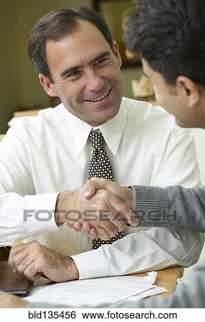 Stock Photograph - Hispanic man and businessman shaking hands. Fotosearch