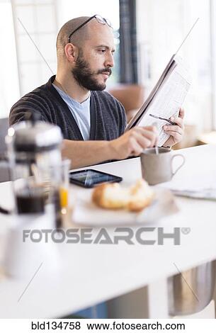 Hispanic man reading newspaper at breakfast View Large Photo Image Stock Photo - Hispanic man reading newspaper at breakfast. Fotosearch