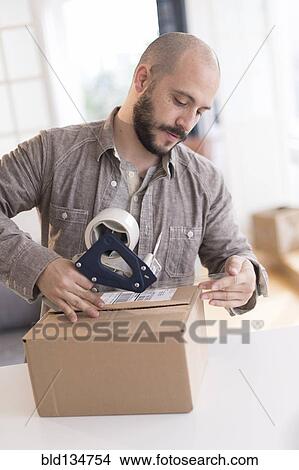 Hispanic man taping cardboard box View Large Photo Image Picture - Hispanic man taping cardboard box. Fotosearch