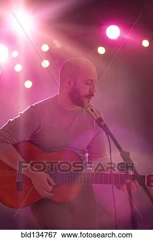 Hispanic musician playing guitar on stage View Large Photo Image Stock Photo - Hispanic musician playing guitar on stage. Fotosearch