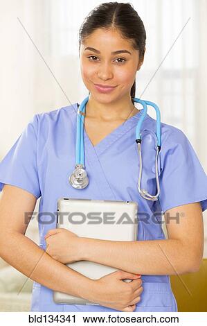 Hispanic nurse holding tablet computer View Large Photo Image Stock Image - Hispanic nurse holding tablet computer. Fotosearch