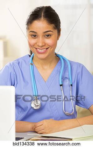 Hispanic nurse smiling at desk View Large Photo Image Stock Photo - Hispanic nurse smiling at desk. Fotosearch