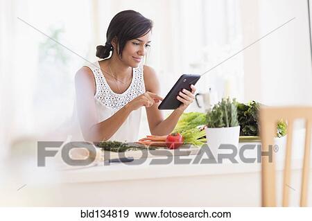 Hispanic woman cooking with digital tablet View Large Photo Image Stock Photo - Hispanic woman cooking with digital tablet. Fotosearch