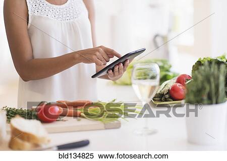 Hispanic woman cooking with digital tablet in kitchen View Large Photo Image Stock Photography - Hispanic woman cooking with digital tablet in kitchen. Fotosearch