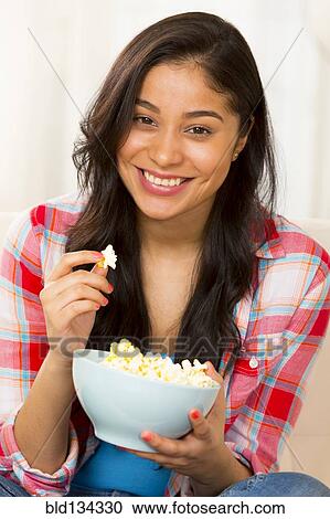 Hispanic woman eating popcorn on sofa View Large Photo Image Stock Image - Hispanic woman eating popcorn on sofa. Fotosearch
