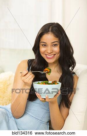 Hispanic woman eating salad on sofa View Large Photo Image Stock Photograph - Hispanic woman eating salad on sofa. Fotosearch