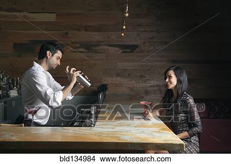 Picture - Hispanic woman having drink at bar. Fotosearch