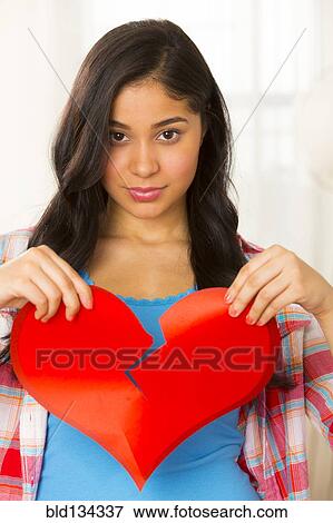 Stock Photo - Hispanic woman holding broken heart. Fotosearch