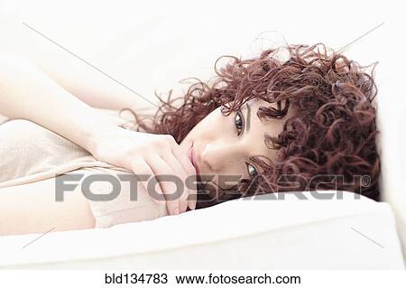 Stock Image - Hispanic woman laying on sofa. Fotosearch