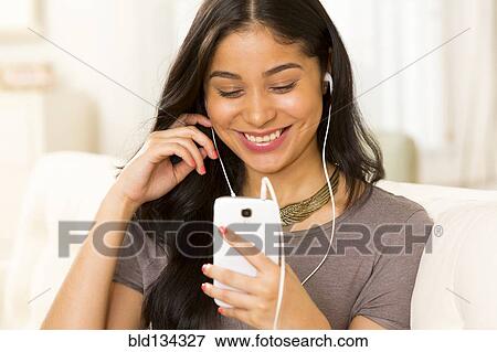 Hispanic woman listening to earphones View Large Photo Image Stock Photo - Hispanic woman listening to earphones. Fotosearch