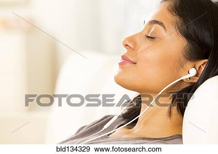 Hispanic woman listening to earphones on sofa View Large Photo Image Stock Photo - Hispanic woman listening to earphones on sofa. Fotosearch