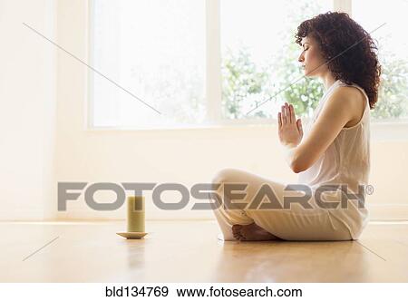 Stock Photo - Hispanic woman meditating with candle. Fotosearch