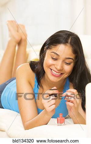 Hispanic woman painting her nails on sofa View Large Photo Image Stock Image - Hispanic woman painting her nails on sofa. Fotosearch