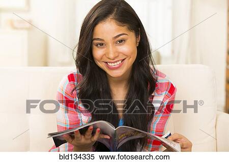 Hispanic woman reading magazine on sofa View Large Photo Image Stock Photography - Hispanic woman reading magazine on sofa. Fotosearch
