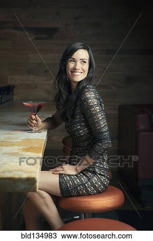 Stock Image - Hispanic woman smiling at bar. Fotosearch