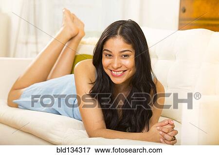 Stock Photo - Hispanic woman smiling on sofa. Fotosearch