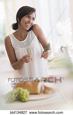 Hispanic woman talking on cell phone and cooking in kitchen View Large Photo Image Stock Photo - Hispanic woman talking on cell phone and cooking in kitchen. Fotosearch