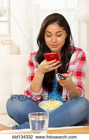 Hispanic woman using cell phone on sofa View Large Photo Image Stock Image - Hispanic woman using cell phone on sofa. Fotosearch
