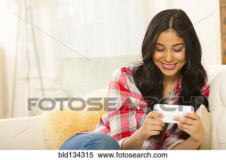 Hispanic woman using cell phone on sofa View Large Photo Image Stock Photography - Hispanic woman using cell phone on sofa. Fotosearch