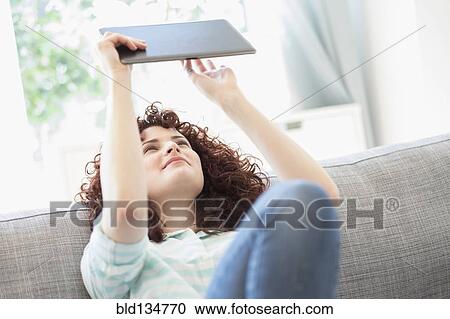 Hispanic woman using digital tablet on sofa View Large Photo Image Stock Image - Hispanic woman using digital tablet on sofa. Fotosearch