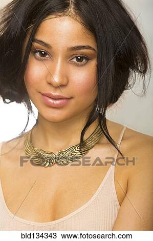 Stock Image - Hispanic woman wearing gold necklace. Fotosearch