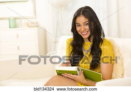 Picture - Hispanic woman writing in notebook. Fotosearch