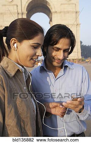 Indian couple listening to headphones by monument, Delhi, India View Large Photo Image Stock Image - Indian couple listening to headphones by monument, Delhi, India. Fotosearch