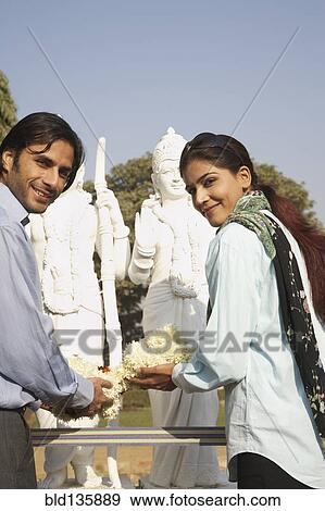 Indian couple offering flowers to shrine View Large Photo Image Stock Photo - Indian couple offering flowers to shrine. Fotosearch