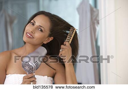Stock Photo - Indian woman blow drying her hair. Fotosearch