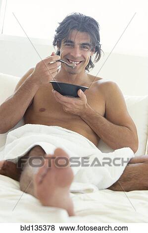 Man eating cereal in bed View Large Photo Image Stock Photo - Man eating cereal in bed. Fotosearch