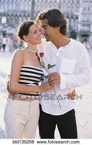 Man giving girlfriend flower on city street View Large Photo Image Stock Photo - Man giving girlfriend flower on city street. Fotosearch