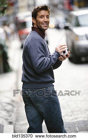 Man holding ball on city street View Large Photo Image Stock Image - Man holding ball on city street. Fotosearch