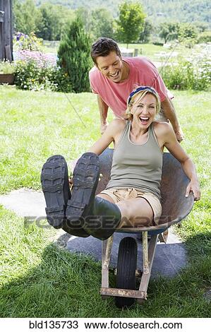 Man pushing girlfriend in wheelbarrow View Large Photo Image Stock Image - Man pushing girlfriend in wheelbarrow. Fotosearch