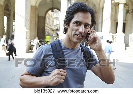 Man talking on cell phone on city street View Large Photo Image Stock Photo - Man talking on cell phone on city street. Fotosearch