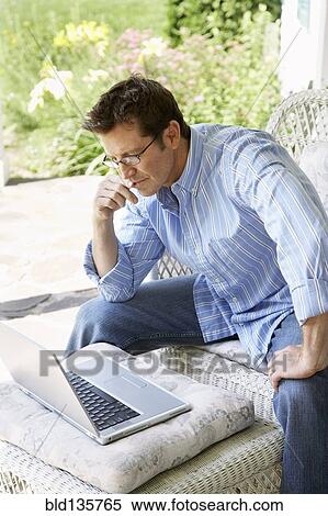Man using laptop on patio View Large Photo Image Stock Photography - Man using laptop on patio. Fotosearch